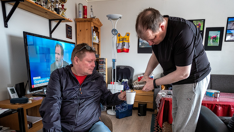 Kautokeino01_800px.jpg Stående mann skjenker kaffe til en annen mann fra en termos.