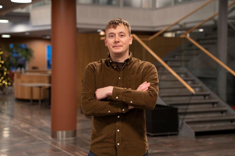Michael_Kampffmeyer_UIT_26803_Foto_Jakob__Bjorvig_Henriksen.jpg Portrettbilde av ung professor med foldete armer foran trapp og gang i et større bygg