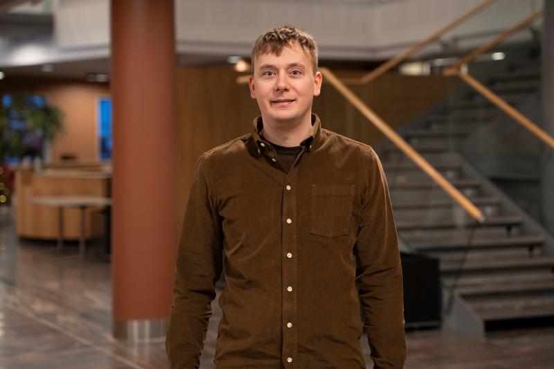 Michael_Kampffmeyer_UIT_26800_Foto_Jakob__Bjorvig_Henriksen.jpg Portrettbilde av ung forsker med brun skjorte inne på en forskningspark