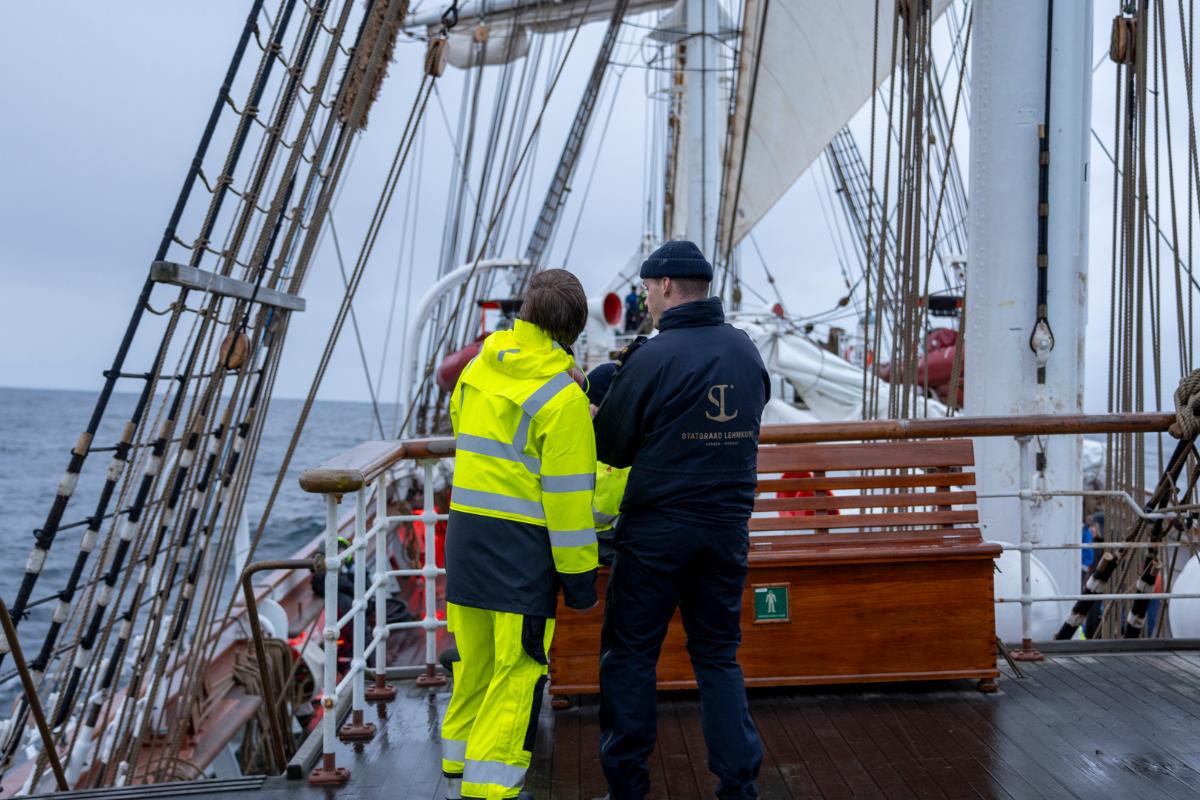To personer står med ryggen til om bord på et seilskip