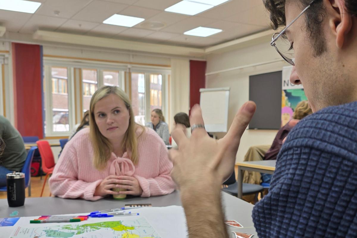 20250313_162001.jpg To personer snakker sammen ved et bord.