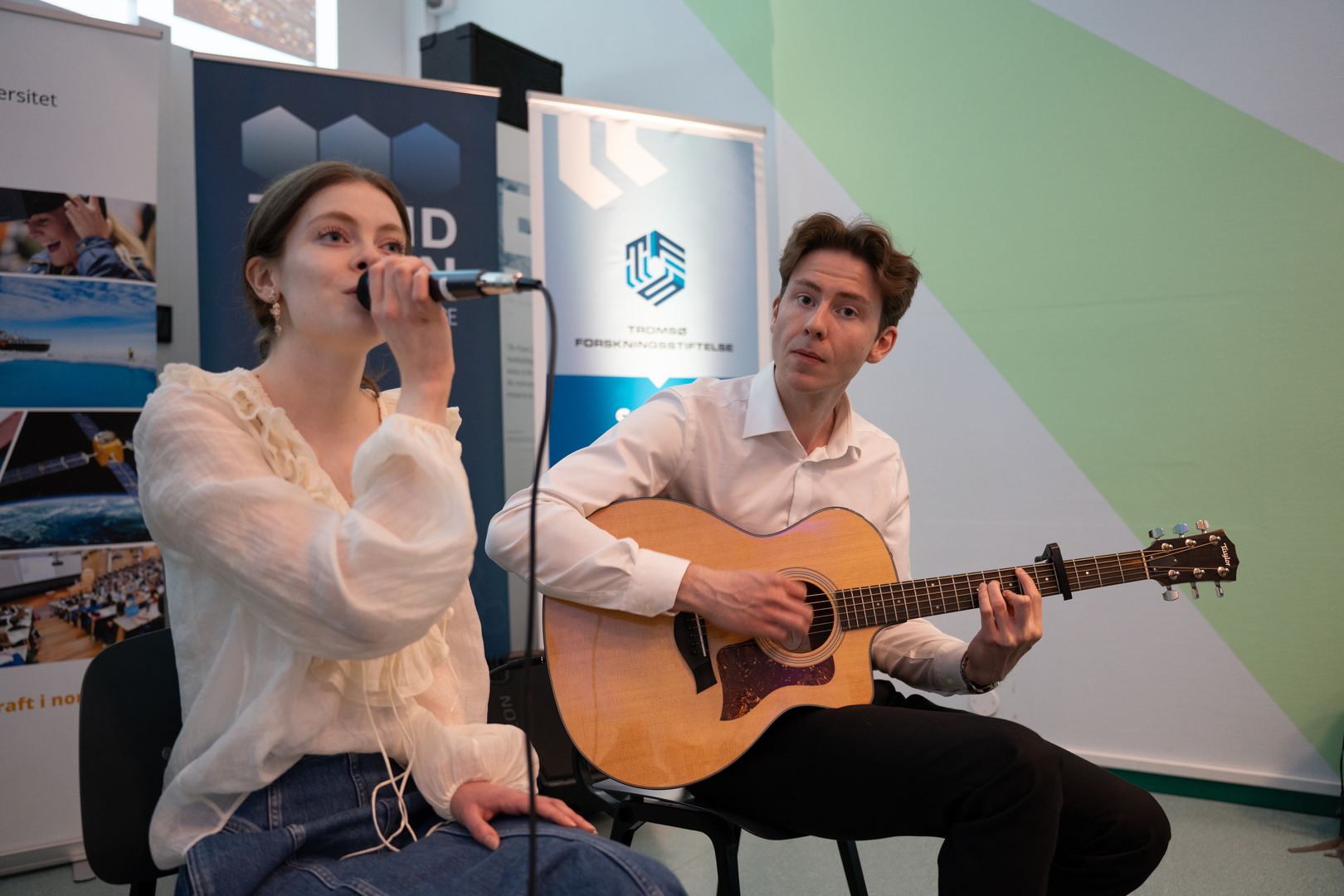 two people sitting and performing music.