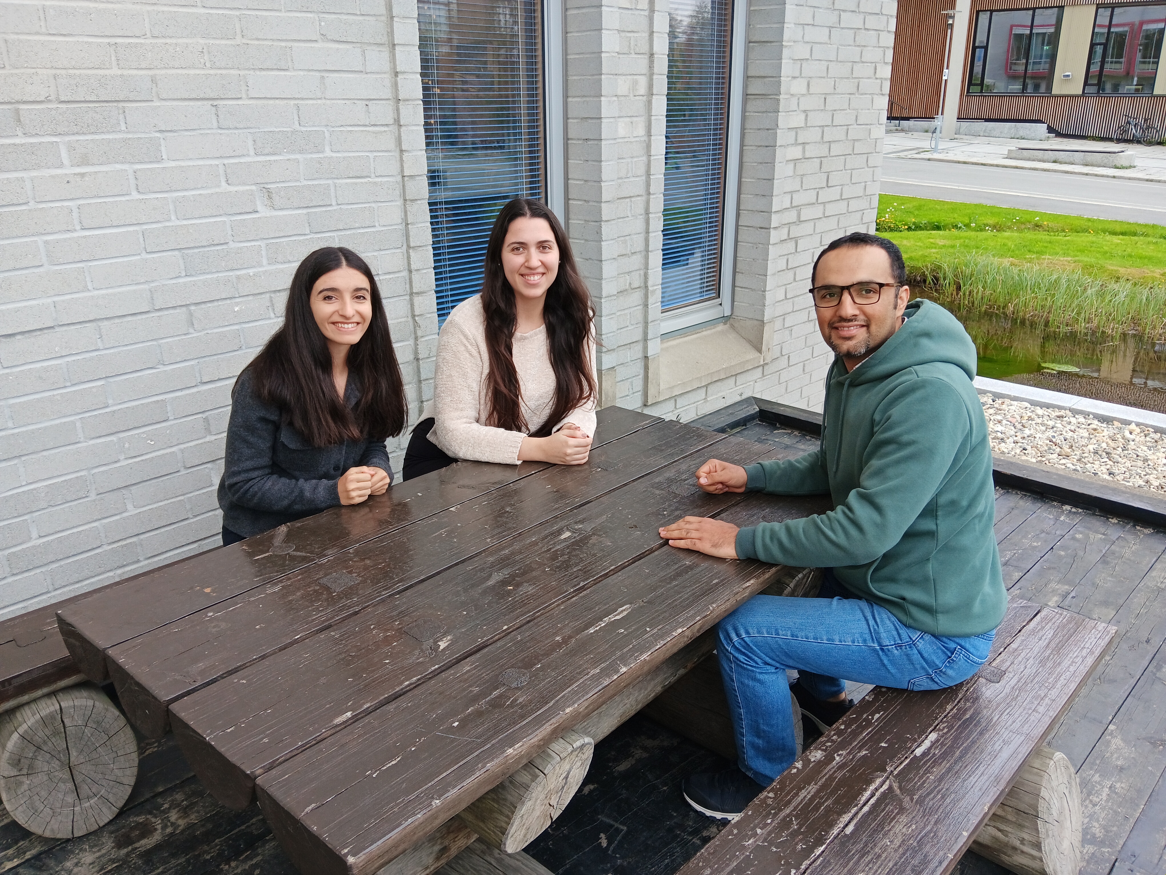 Three people sitting by a table outdoors.
