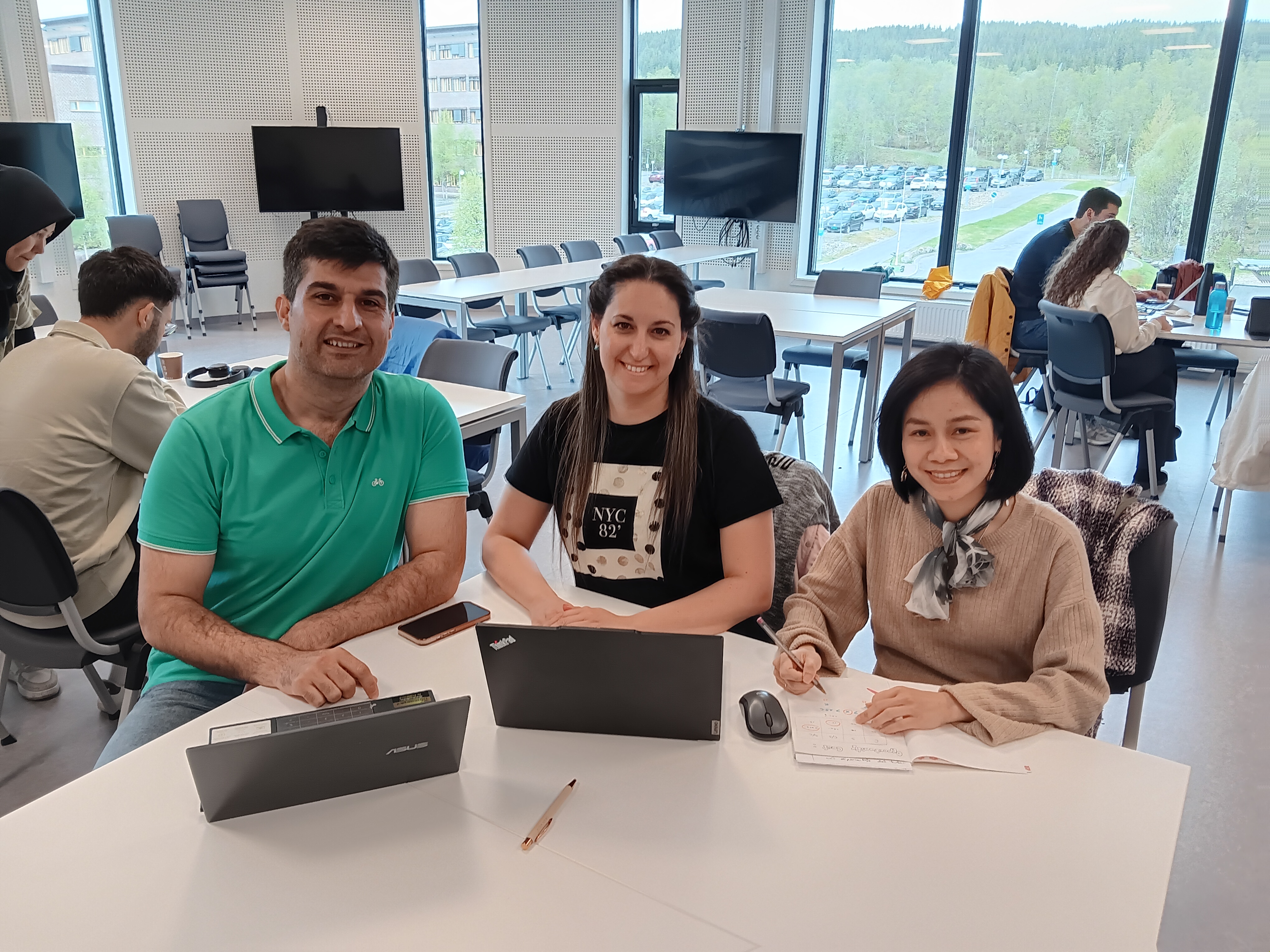 Three people sitting by a table.