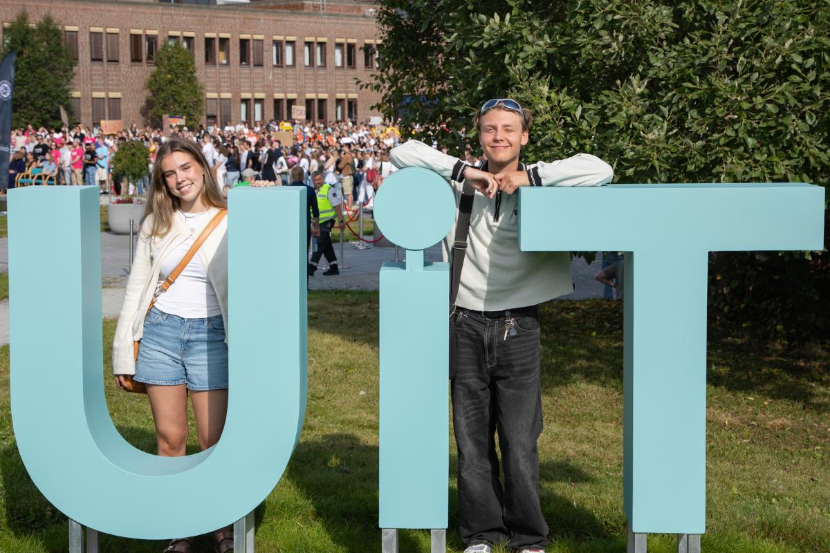 en jente og en gutt som smiler og står ved tre store bokstaver