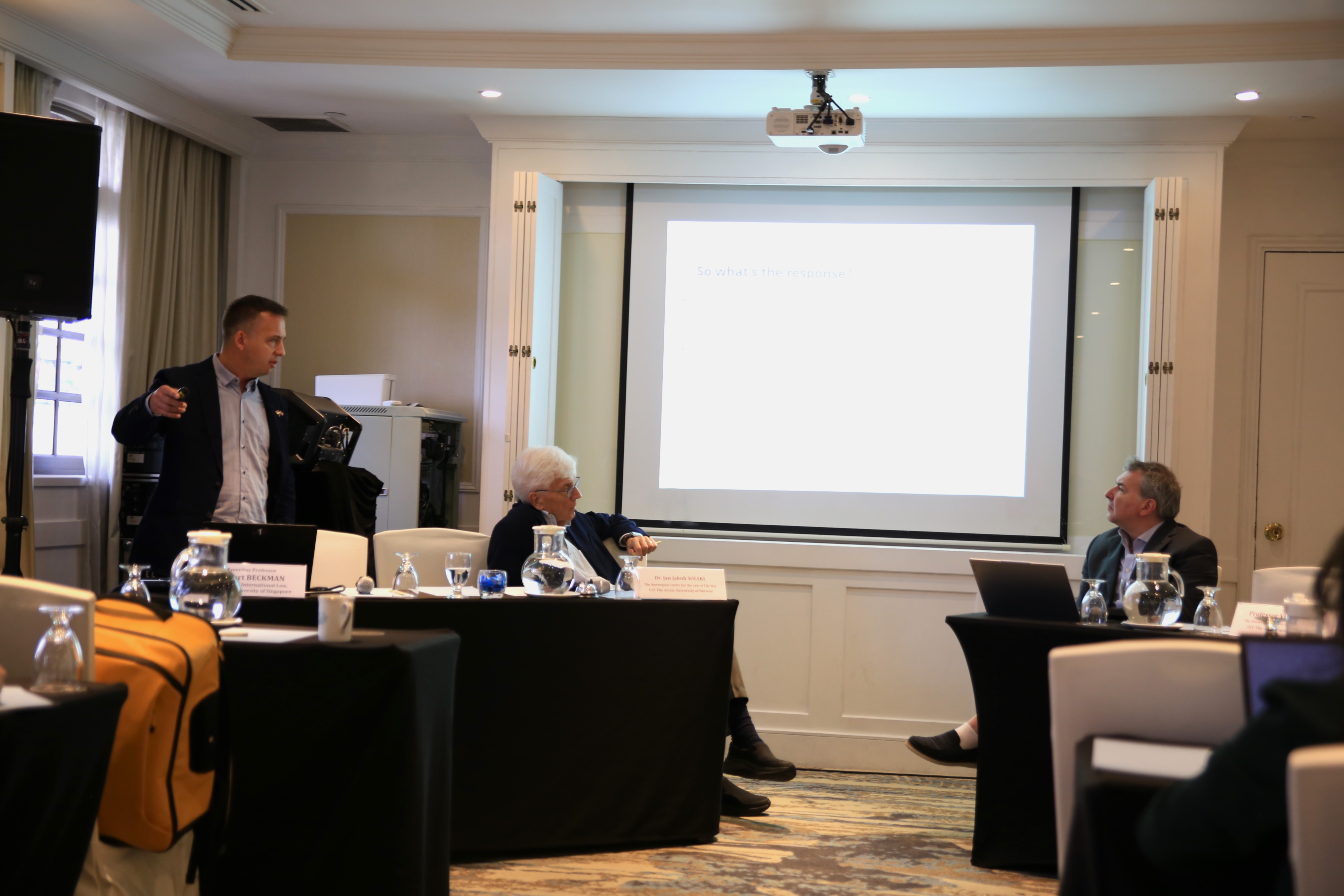 Three men discussing at the workshop, screen in the background. 