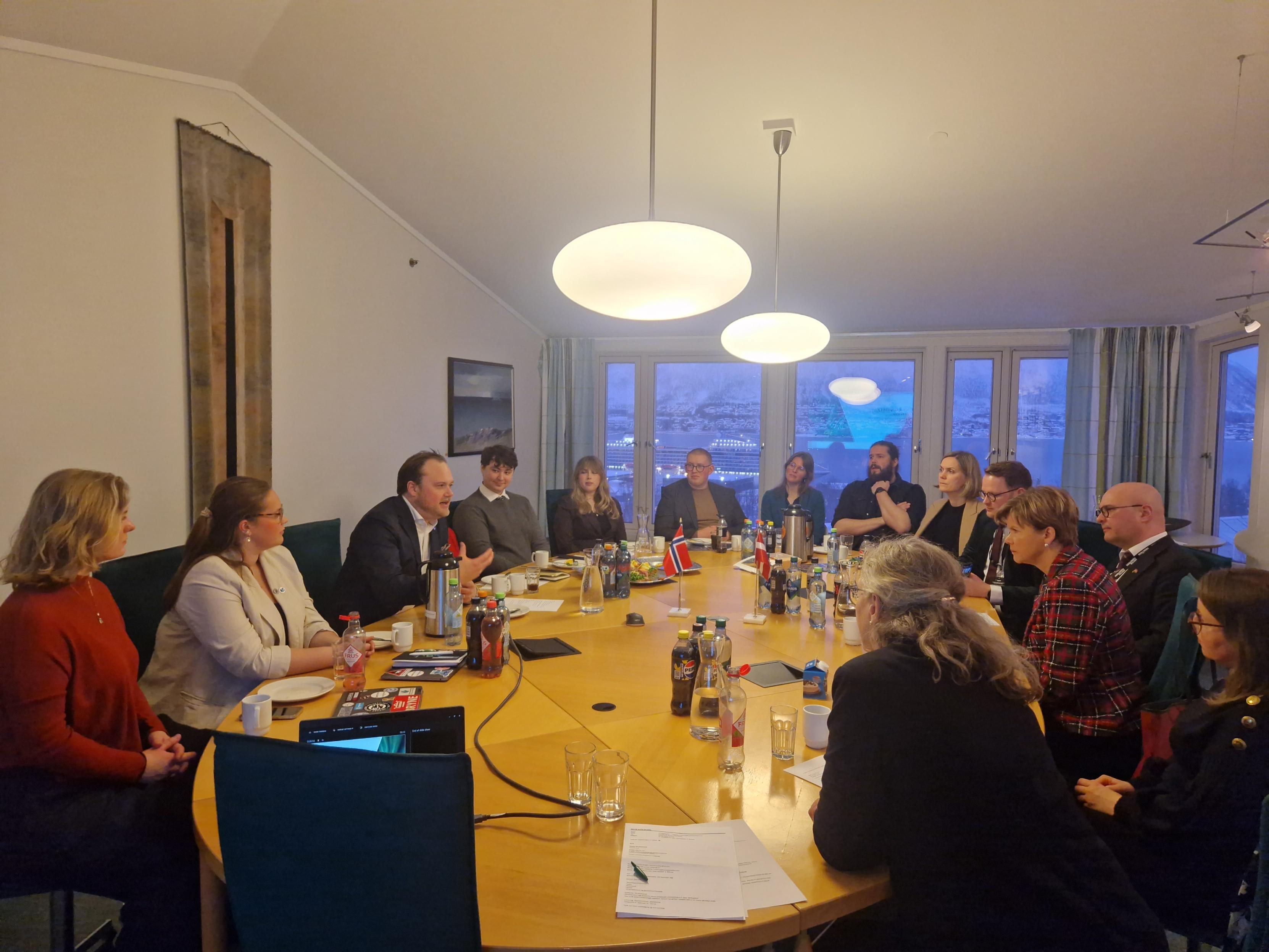 multiple people, sitting around a table, discussing