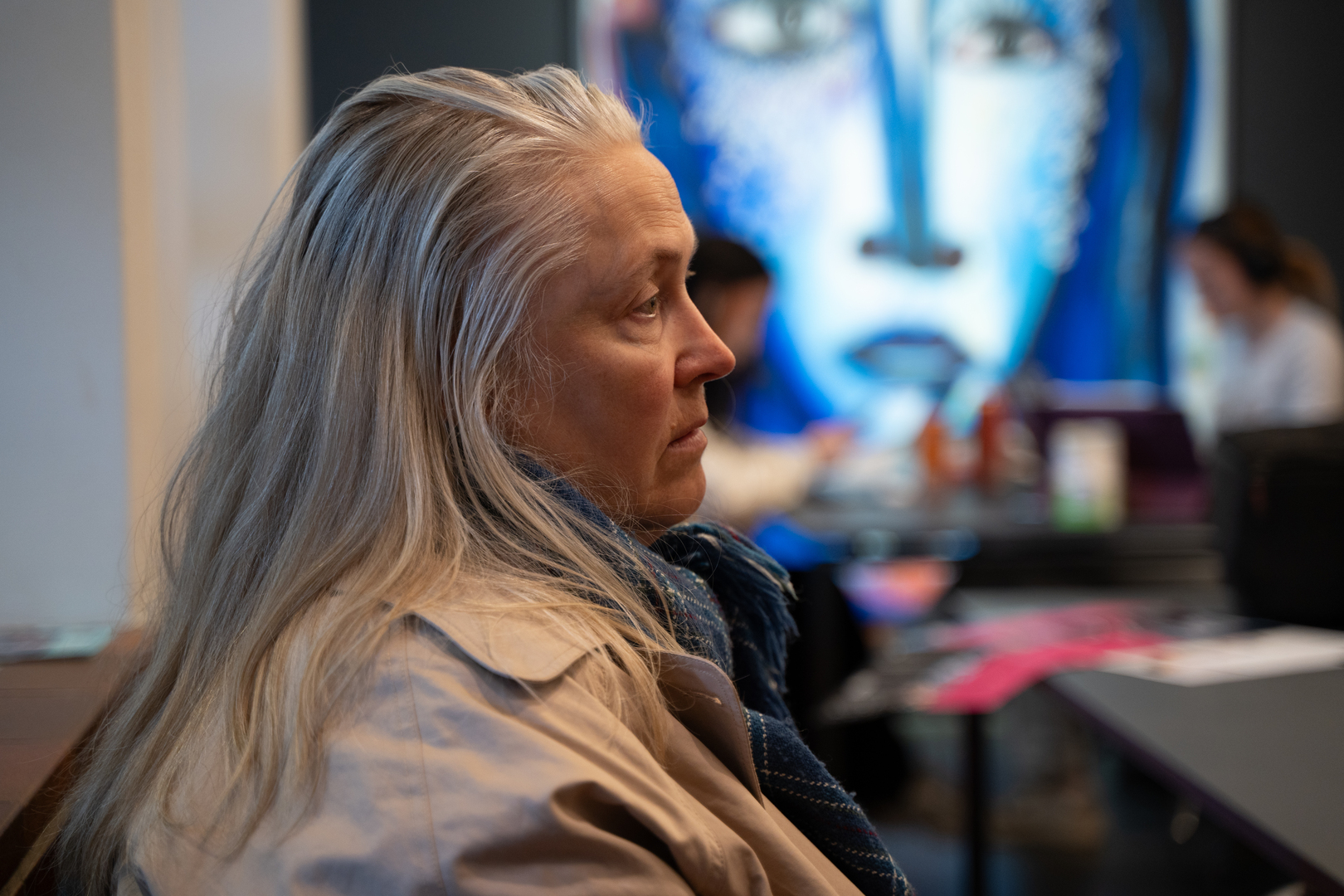 Alvorlig kvinne med karakteristik bl&aring;tt maleri i bakgrunnen. 