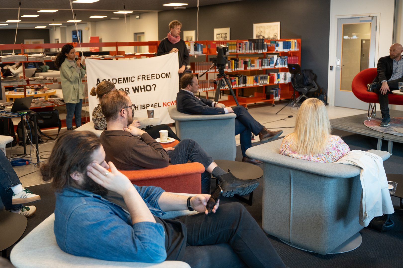 Folk i lenestoler p&aring; samtale-arrangement p&aring; et universitetsbibliotek. 